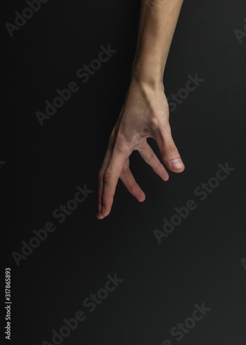 Female hand touches something on a black background.