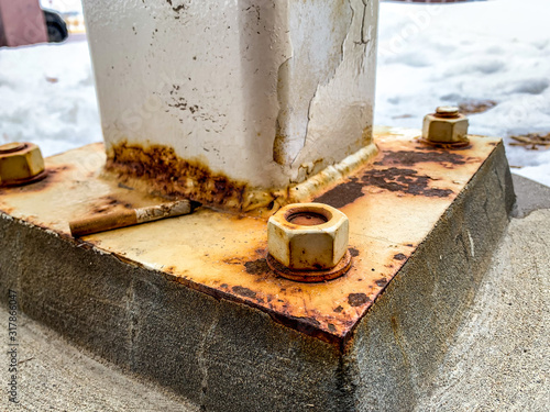 Photography Structural support on concrete with rusted anchor bolts, chipped paint, and burn