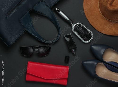 Women's accessories on a black background. Hat, leather bag, comb, sunglasses, perfume bottle. Top view