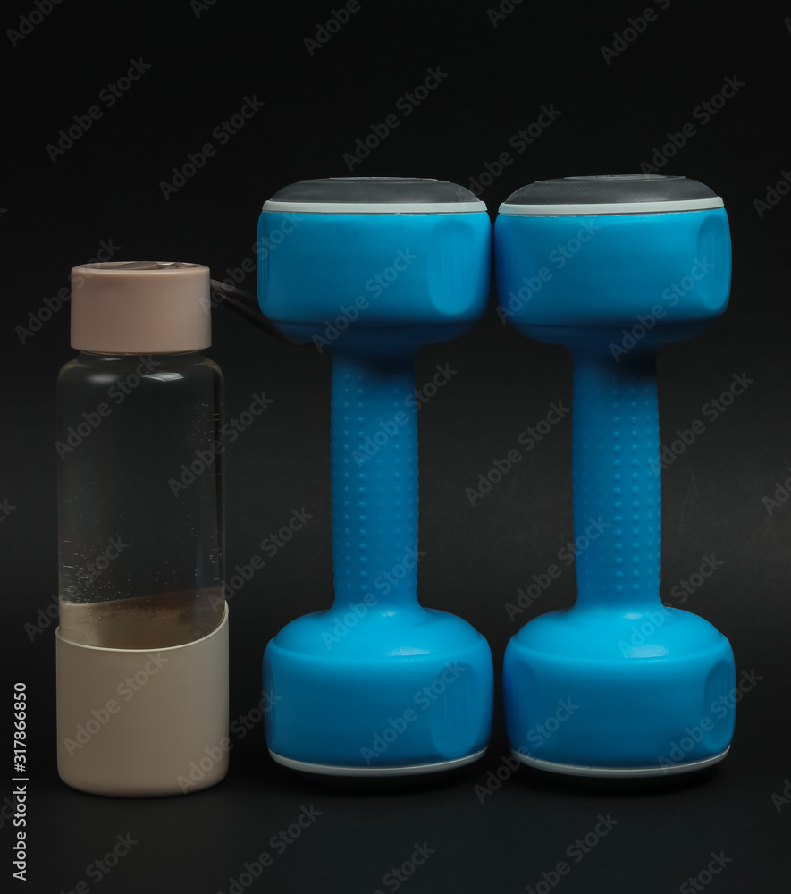 Accessories for fitness and sports on a black background. Dumbbells, bottle of water. Accessories for fitness and sports on a black background. Dumbbells, bottle of water.