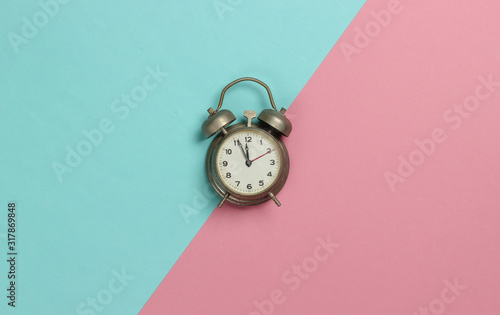 Retro alarm clock on pink blue pastel background. 11:55 am. New Year. Top view