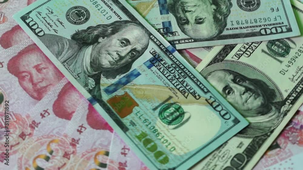 compilation on the theme of trade wars between the US and China. Close up of 100 dollar banknotes fly on chinese yuan banknote compilation on the theme of trade wars between the US and China. Close up of 100 dollar banknotes fly on chinese yuan banknote