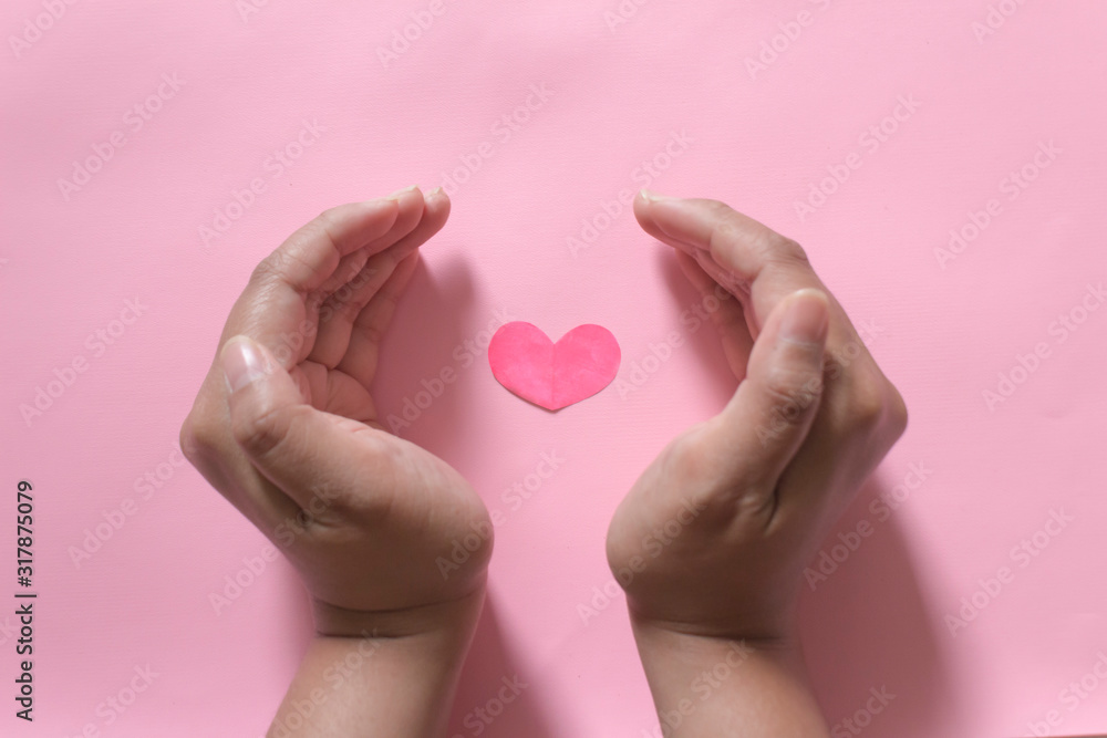 Heart in hands with pink background. Valentine's day concept.  Heart healthcare concept.