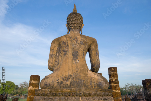 View from the back of ancient sculpture of a sitting Buddha against  blue sky. Sukhothai  Thailand