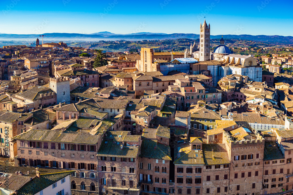 Aerial view of Siena cityscape at a bright sunny day. Siena Cathedral is visible in the right background.