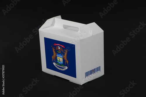 Michigan flag and barcode on white box with black background, paper packaging for put products. The concept of Michigan trading. photo