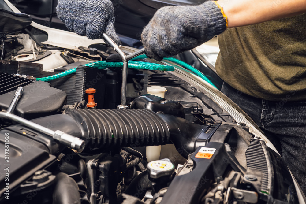 Mechanic hands working holding a wrench and socket on the engine in car at garage .service and maintenance concept . selective focus Mechanic hands working holding a wrench and socket on the engine in car at garage .service and maintenance concept . selective focus