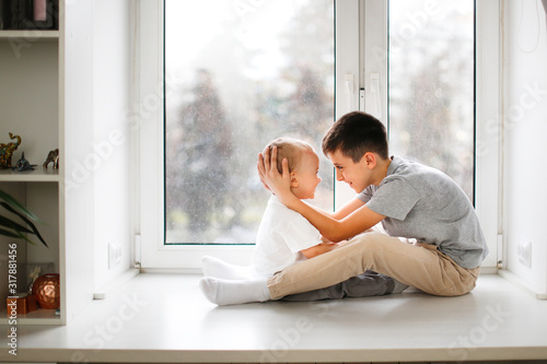 Fotografie, Obraz cute boys hugs by window, brothers