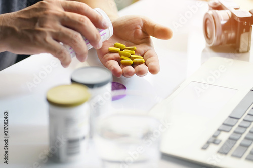 Business man pouring the pills vitamin out of the white bottle in hand at home office.Healthcare and medicine concept. selective focus