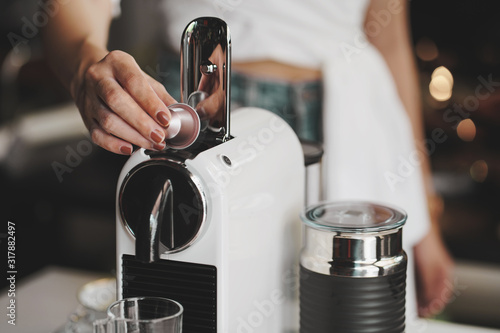 women holding coffee capsules and put in espresso machine with empty cup of coffee at kitchen . photo