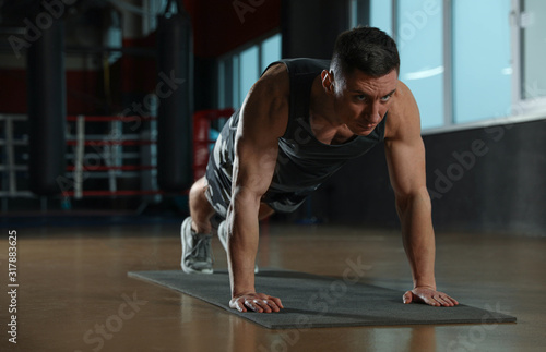 Man doing plank exercise in modern gym