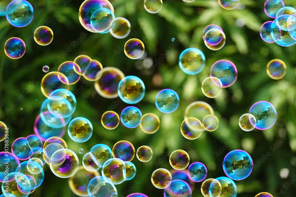 Many soap bubbles on a blurred green nature background.
