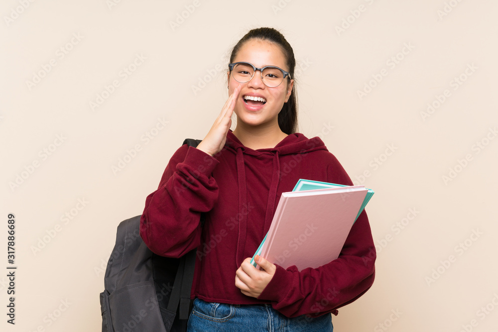 Obraz premium Young student Asian girl woman over isolated background shouting with mouth wide open