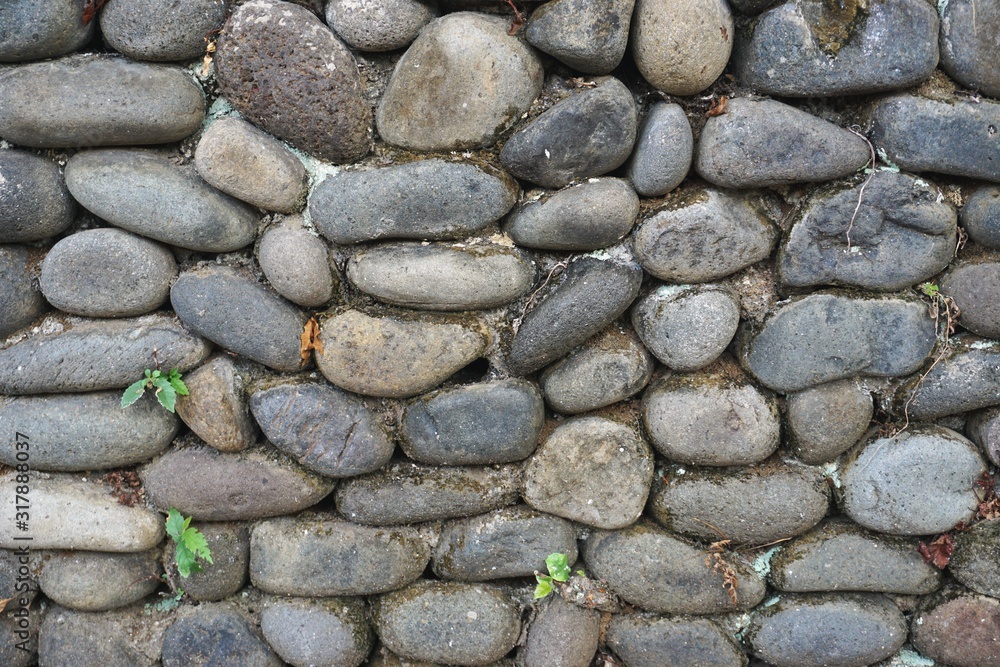 Stone wall with rounded river rocks set in mortar Stone wall with rounded river rocks set in mortar
