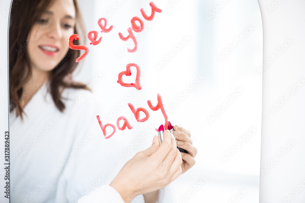 Hand of girl in bathrobe writing love message and drawing heart with lipstick Hand of girl in bathrobe writing love message and drawing heart with lipstick