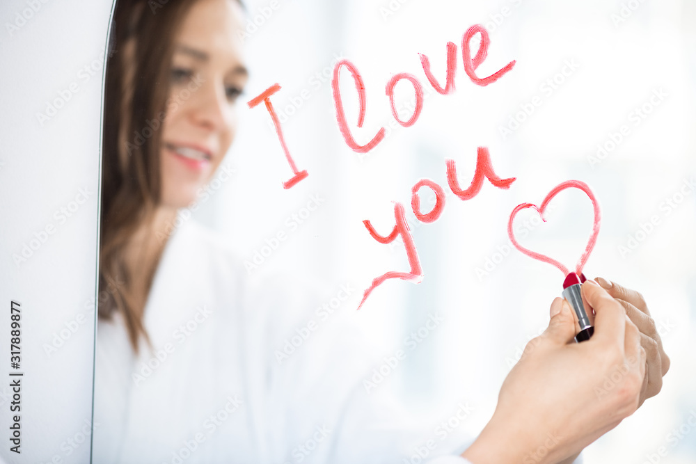 Hand of young amorous female writing love message and drawing small heart Hand of young amorous female writing love message and drawing small heart