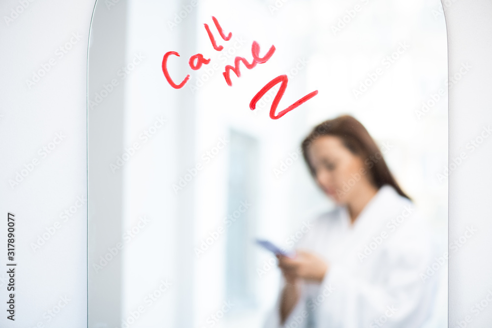 Part of mirror with asking for call written with lipstick and reflection of girl Part of mirror with asking for call written with lipstick and reflection of girl