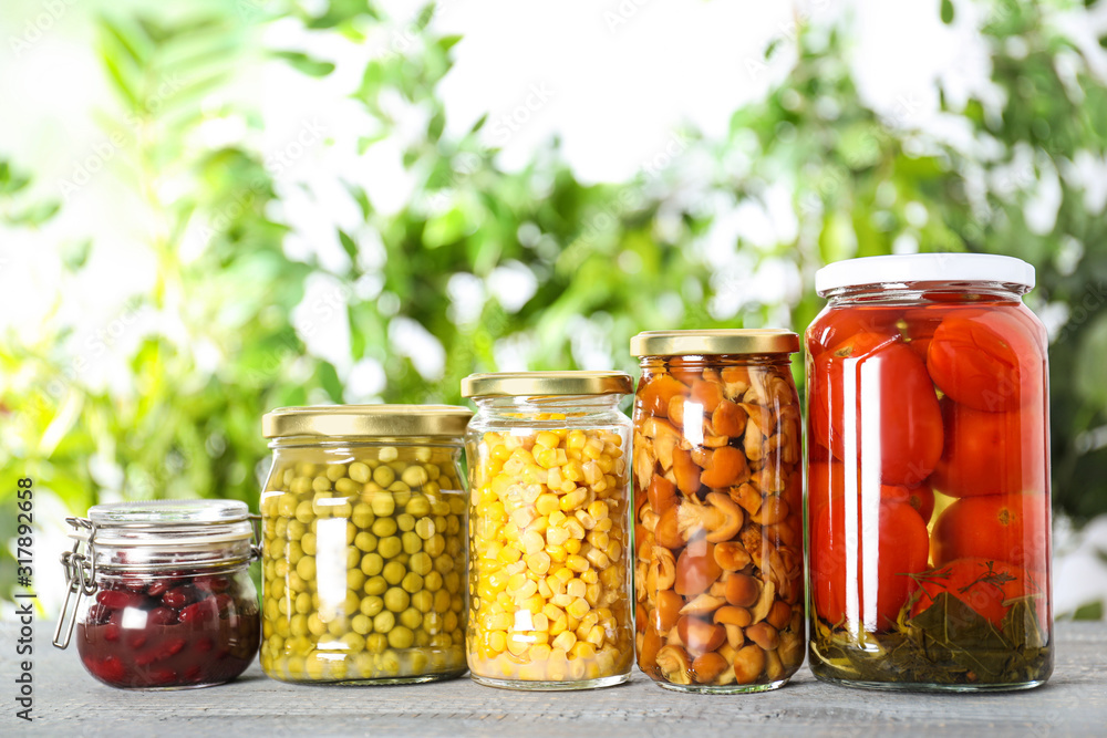 Glass jars of different pickled vegetables on wooden table Glass jars of different pickled vegetables on wooden table