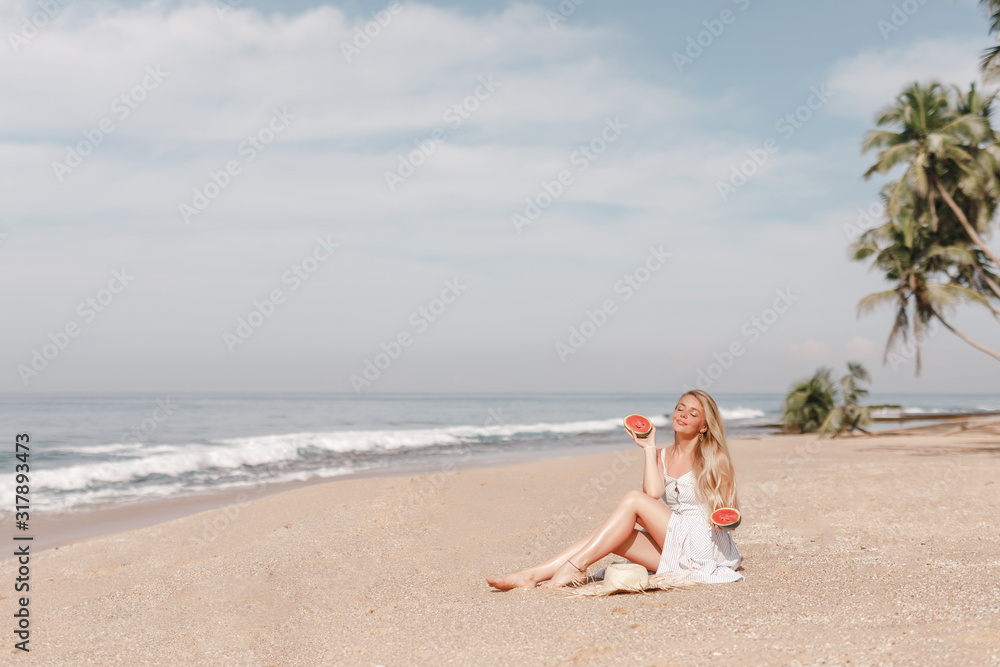 Happy young woman eating watermelon on tropical sand beach. Youth lifestyle. Happiness, joy, holiday, beach, summer concept. Happy young woman eating watermelon on tropical sand beach. Youth lifestyle. Happiness, joy, holiday, beach, summer concept.