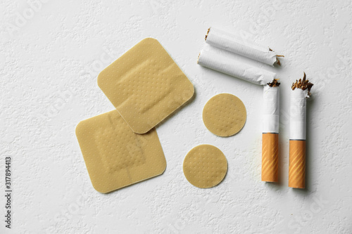 Nicotine patches and broken cigarettes on white background, flat lay photo