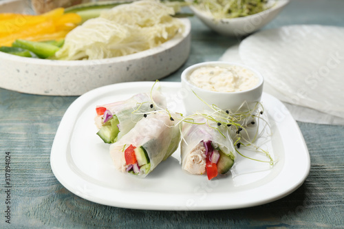 Delicious rolls wrapped in rice paper served on light blue wooden table