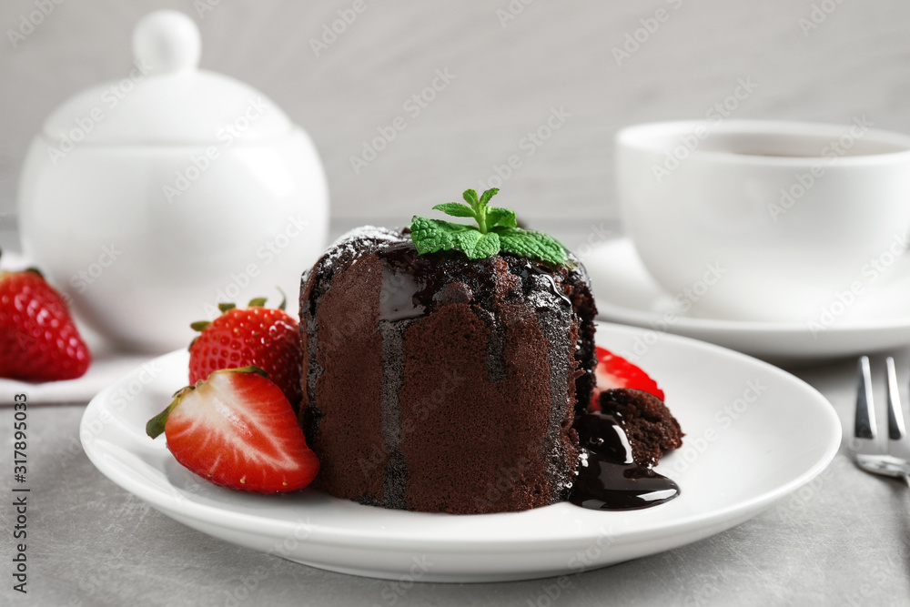 Delicious warm chocolate lava cake with mint and strawberries on table Delicious warm chocolate lava cake with mint and strawberries on table