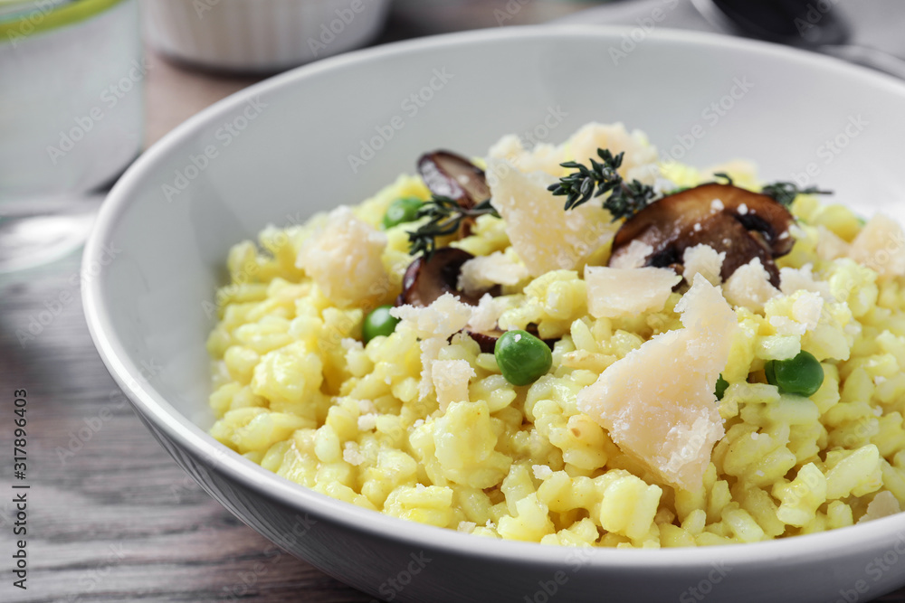 Delicious risotto with cheese and mushrooms on wooden table, closeup Delicious risotto with cheese and mushrooms on wooden table, closeup
