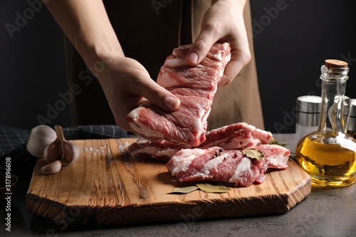 Fototapeta Naklejka Na Ścianę i Meble -  Man holding raw ribs at grey table, closeup