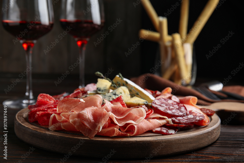 Tasty prosciutto with other delicacies served on wooden table, closeup Tasty prosciutto with other delicacies served on wooden table, closeup