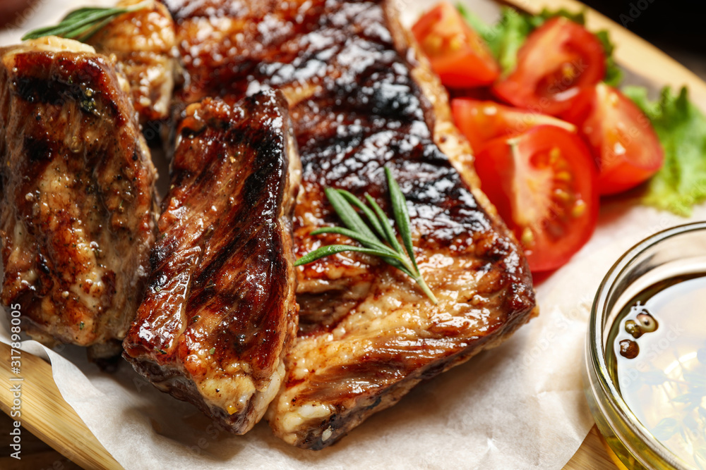 Delicious grilled ribs with rosemary on table, closeup Delicious grilled ribs with rosemary on table, closeup