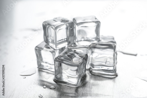 Crystal clear ice cubes with water drops on metal surface, closeup