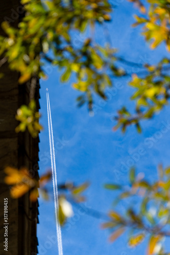 The white plane flies in the sky, the jet engine makes the white line of smoke in the blue sky, between two bridges. photo