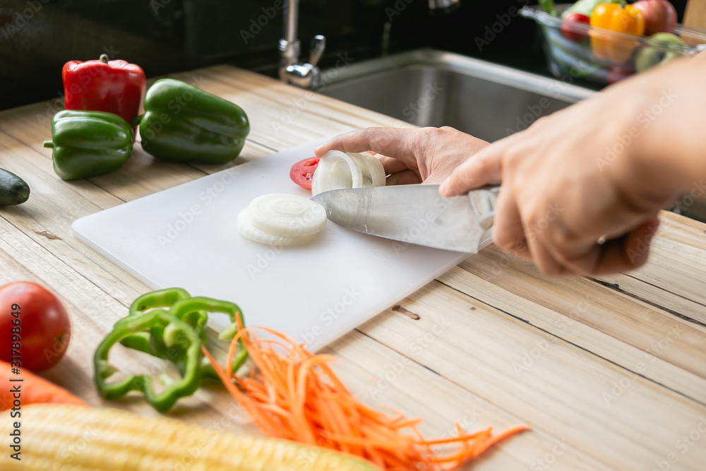Close-up man cooking and slicing fresh vegetables on a rustic kitchen worktop, healthy eating concept, flat lay