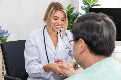 Woman Caucasian professional doctor hand holding the pulse with senior man patient at hospital room. © Suthiporn