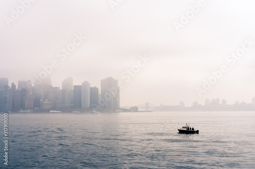 A small fishing boat on the upper Bay on the background Lower manhattan in the fog