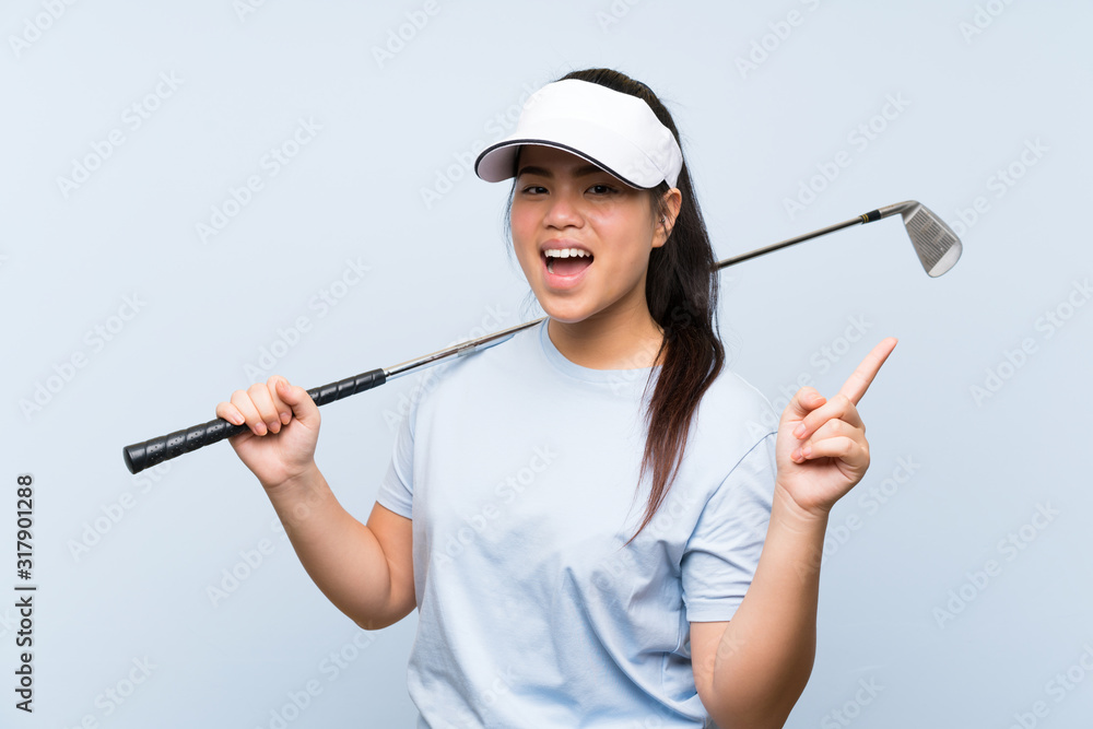 Young golfer Asian girl over isolated blue background surprised and pointing finger to the side Young golfer Asian girl over isolated blue background surprised and pointing finger to the side