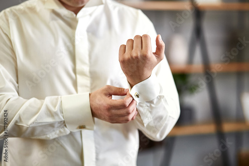 businessman dresses white shirt, male hands closeup,groom getting ready in the morning before wedding ceremony © bondvit
