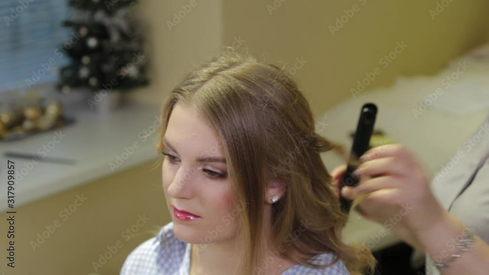 Professional hairdresser doing evening hairstyle for girl.