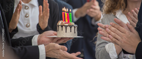 Staff friends surprise singing happy and clapping to celebrate birthdays with birthday cake and there were candles on the cake party in meeting 