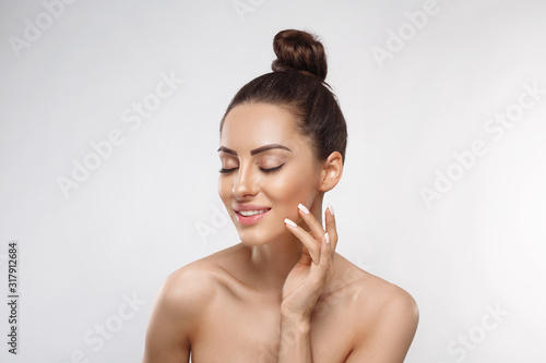 Beauty and Spa Concept. Beautiful Young Woman with Clean Fresh Skin touch face. Facial treatment. Girl Female With Natural Makeup.Cosmetology. Skin Care photo