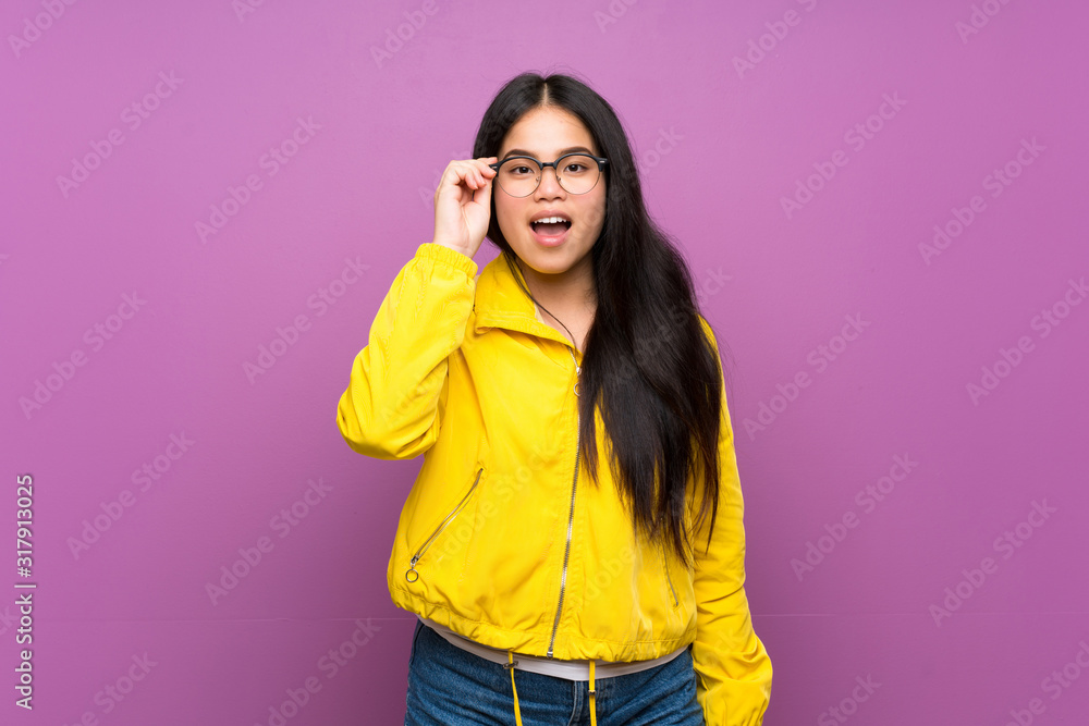 Young teenager Asian girl over isolated purple background with glasses and surprised Young teenager Asian girl over isolated purple background with glasses and surprised