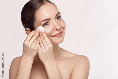 Woman Cleaning Face With White Pad. Beautiful Girl Removing Makeup White Cosmetic Cotton Pad. Happy Smiling Female Taking Off Makeup From Facial Skin With Cosmetic Pad. Face Skin Care. photo
