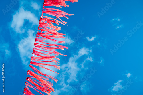 String of bright pink streamers flutters in the wind against vibrant blue sky
