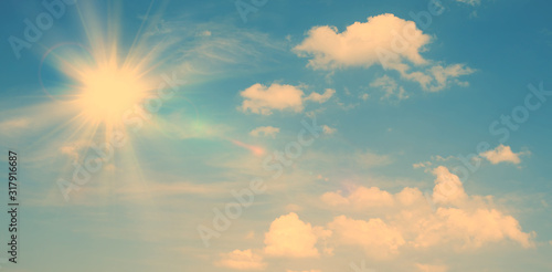 Sunny natural background, blue sky with sun and white clouds vintage background.