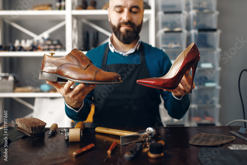 Fotografie Bootmaker shows repaired shoes, footwear repair