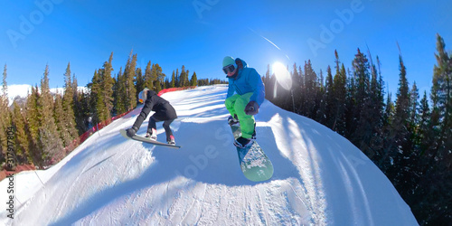 SELFIE: Two snowboarders riding down the fun park catch air and do tricks.