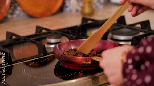 Girl stir coffee beans with a spatula in a copper skillet photo