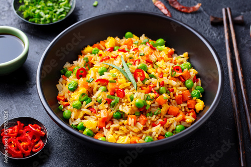 Asian fried rice with egg and vegetables. Dark stone background. Close up.