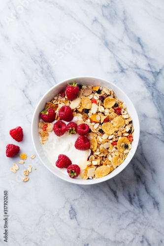 Healthy breakfast. Fresh granola, muesli with yogurt and berries on marble background. Top view. Copy space.