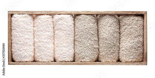 rolled up terry towels in a wooden box isolated on white